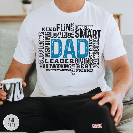 White unisex t-shirt featuring a distressed blue "Dad" typography word art design celebrating fathers with words like kind, inspiring, smart, brave, supportive, and best friend.