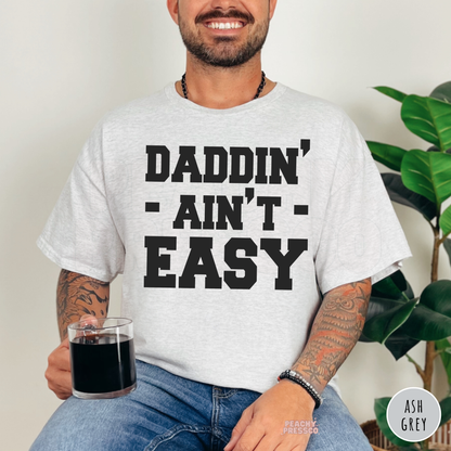 Ash grey graphic t-shirt with the phrase "Daddin' Ain't Easy," perfect for dads with a great sense of humor.