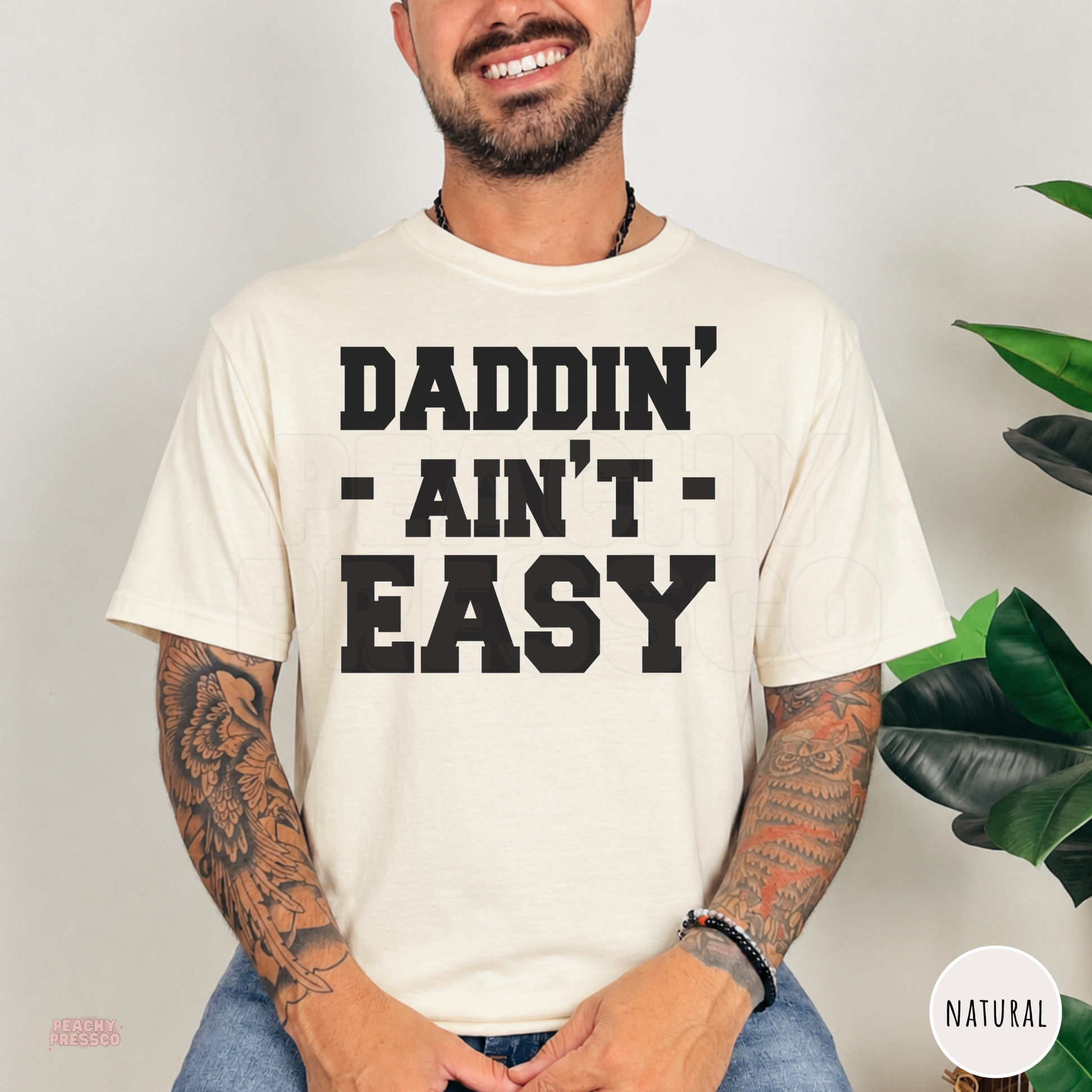 Natural color unisex t-shirt with the bold "Daddin' Ain't Easy" graphic, a unique Father's Day gift idea.
