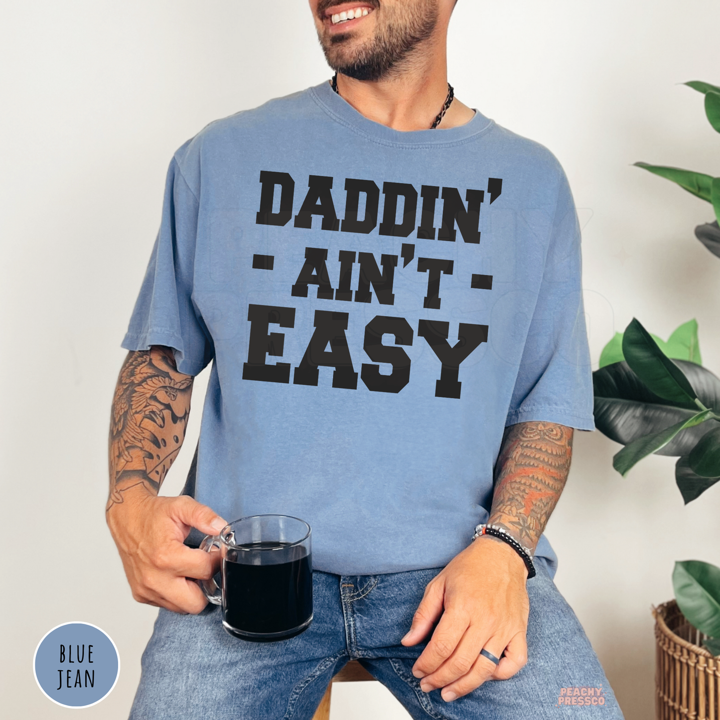 Blue Jean garment-dyed t-shirt featuring the funny "Daddin' Ain't Easy" dad graphic in bold black lettering.