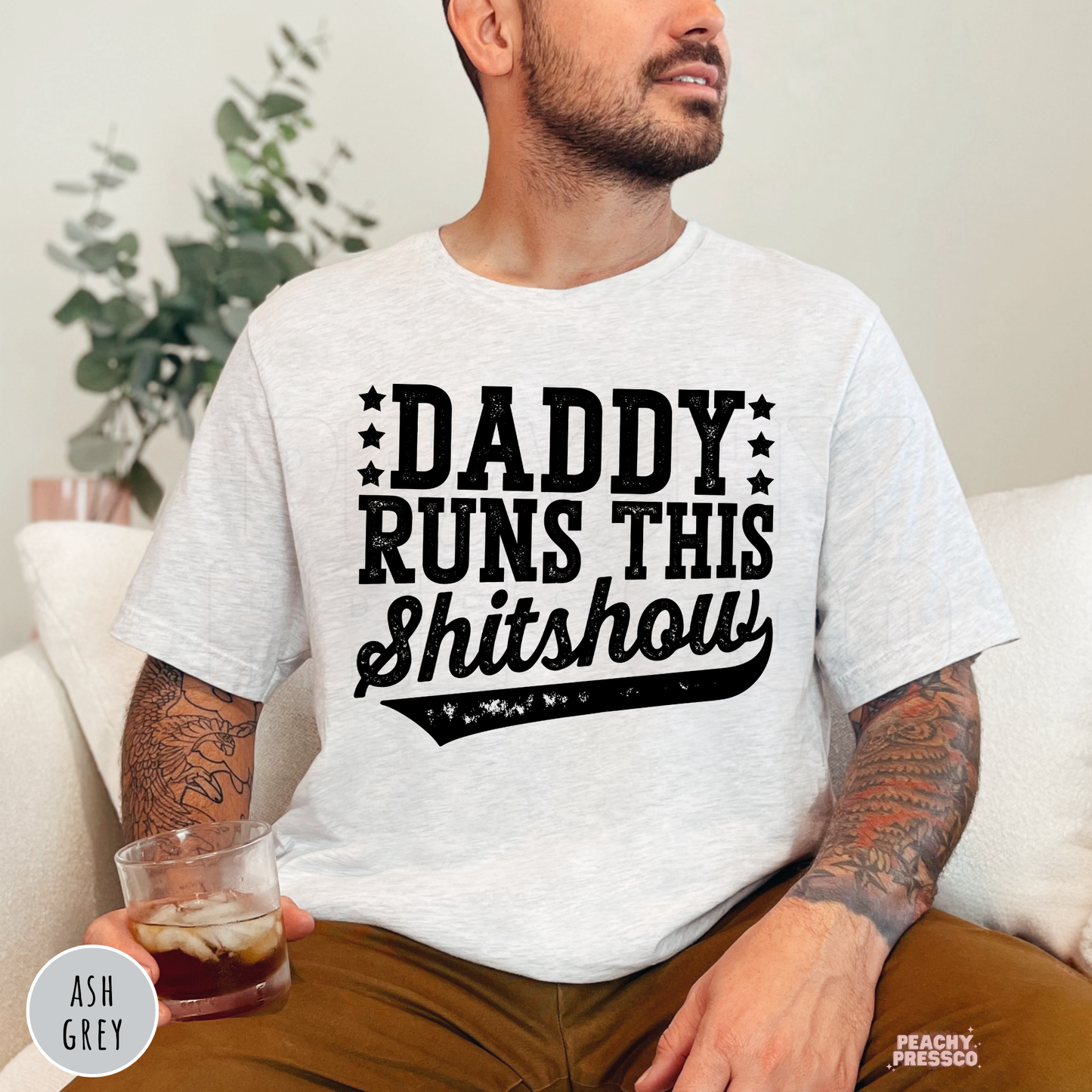 Ash Grey unisex t-shirt featuring the Daddy Runs This Shitshow distressed graphic in black lettering, a humorous Father's Day shirt.