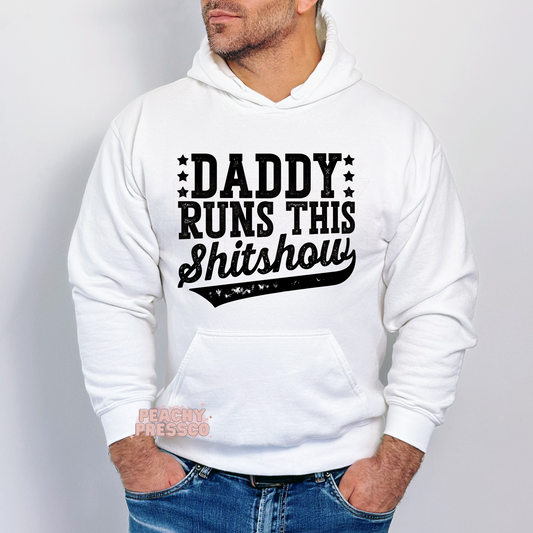 White hoodie featuring the distressed Daddy Runs This Shitshow design in black lettering, a humorous hoodie for dads and Father's Day.
