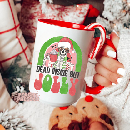 Ceramic Christmas mug with red handle featuring a cool skeleton in a Santa hat and sunglasses holding cocoa with text Dead Inside But Jolly.