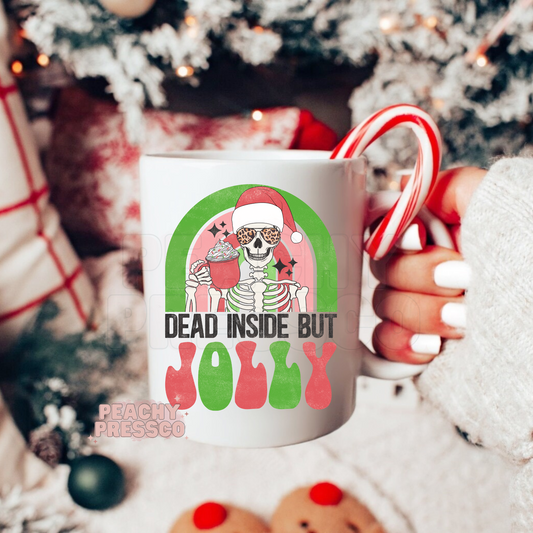 Ceramic Christmas mug featuring a cool skeleton in a Santa hat and sunglasses holding cocoa with text Dead Inside But Jolly.