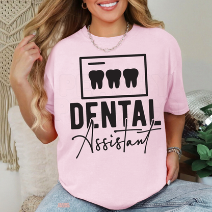 Woman wearing a light pink Dental Assistant graphic T-shirt with three black teeth and bold lettering, perfect for dental office staff.