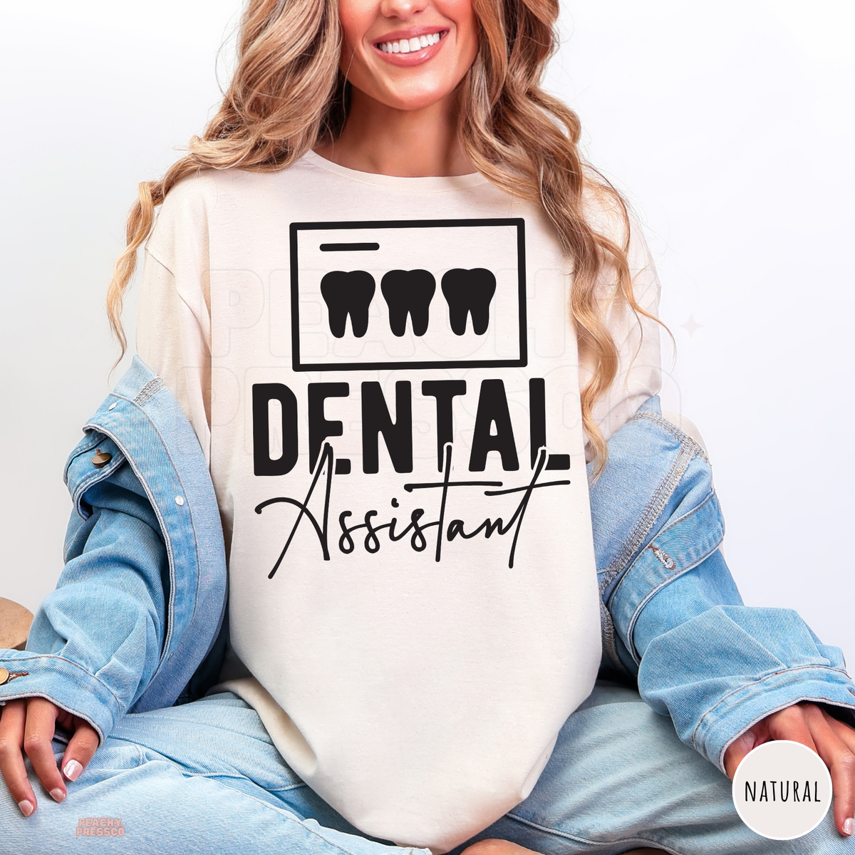 Woman modeling a natural Dental Assistant shirt with black tooth graphics and script lettering, a gift idea for dental assistants.