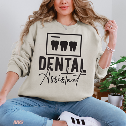 Woman wearing a sand colored Dental Assistant crewneck sweatshirt featuring three tooth icons and bold black dental assistant lettering.