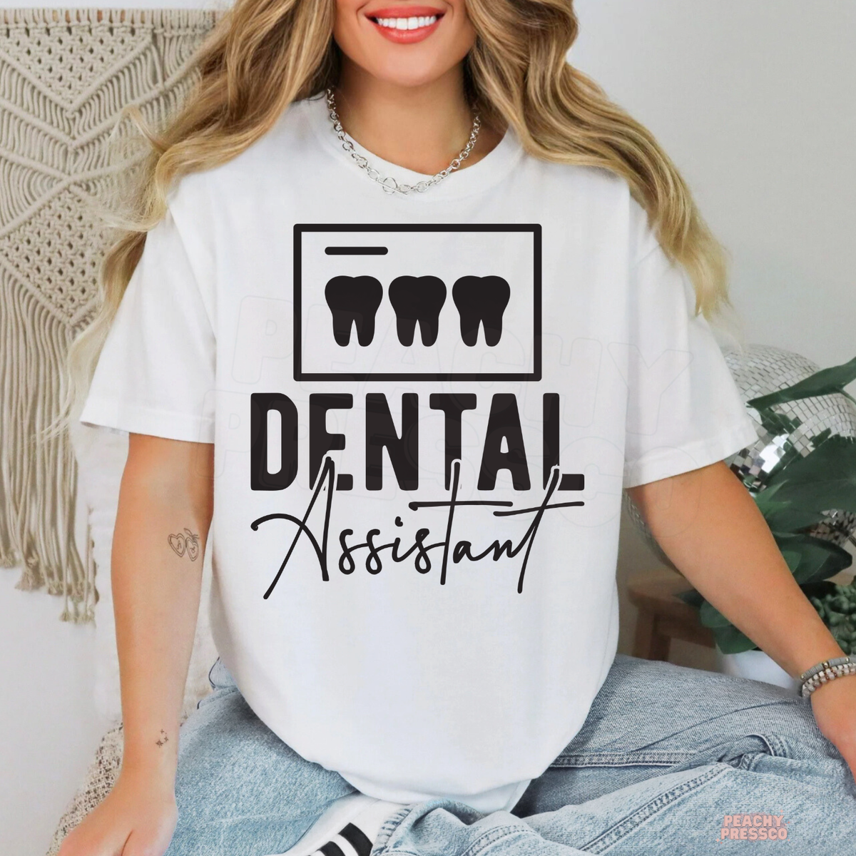 Woman wearing a white Dental Assistant graphic T-shirt featuring a black three-tooth illustration and bold script lettering.