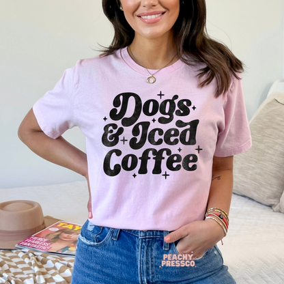 Woman wearing a light pink t-shirt with a vintage "Dogs & Iced Coffee" graphic design in distressed black print.