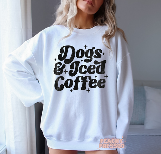 Woman wearing a white crewneck sweatshirt featuring a vintage "Dogs & Iced Coffee" graphic design.