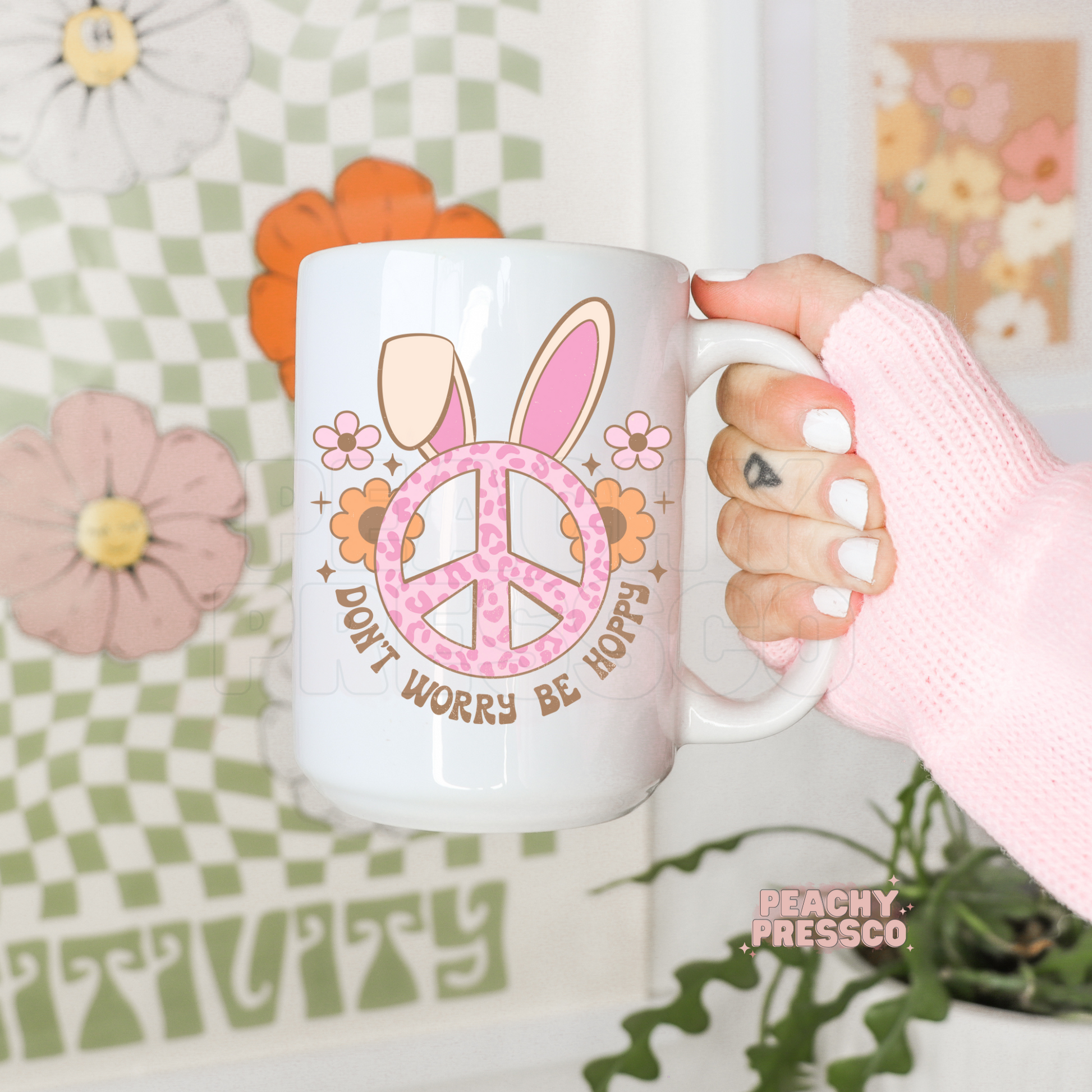 White ceramic coffee mug featuring a pink leopard peace sign with bunny ears, flowers, and the phrase "Don't Worry Be Hoppy."