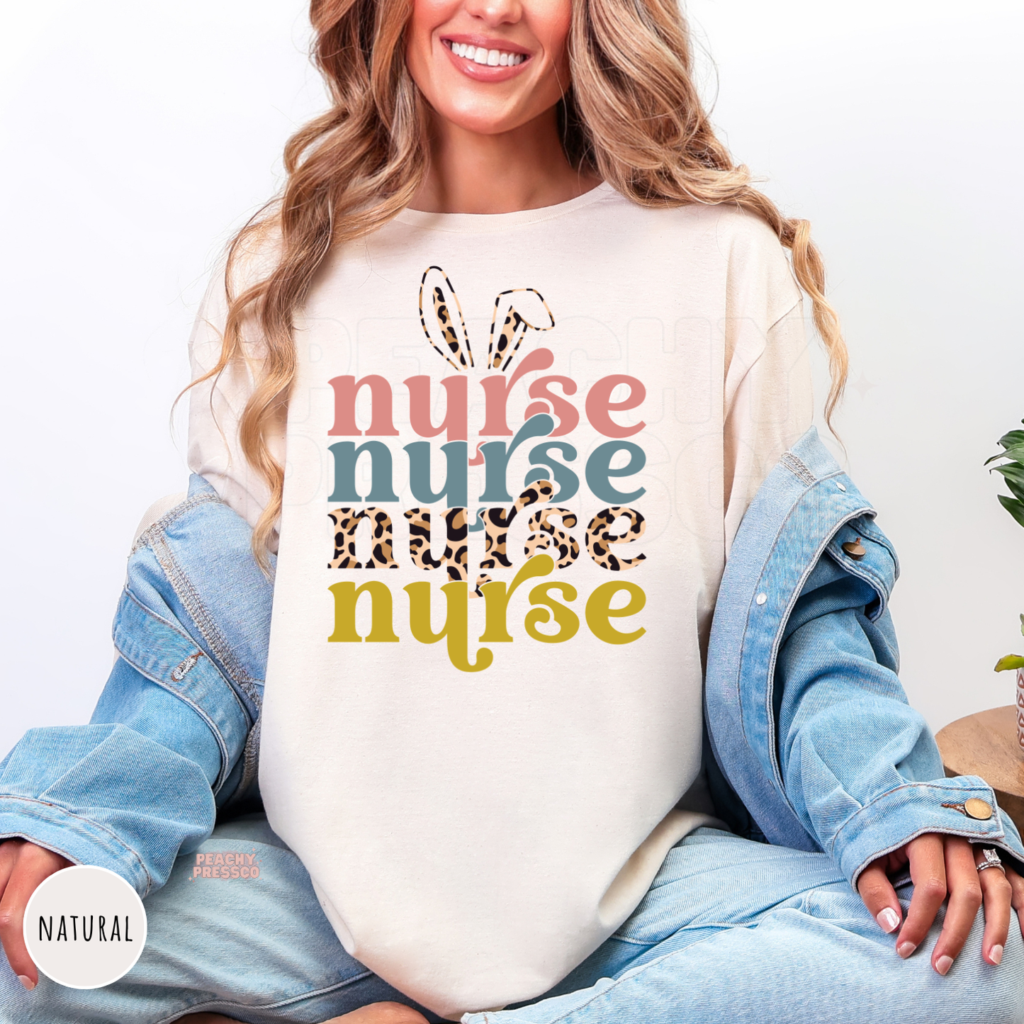 Woman wearing a natural shirt featuring a colorful retro Easter Nurse design with bunny ears and leopard print lettering.