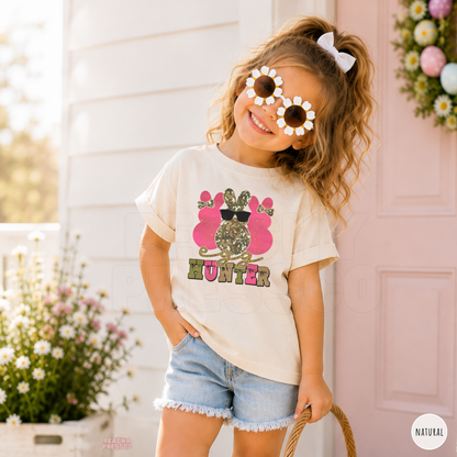 Toddler girl wearing a natural Egg Hunter Easter tee featuring a pink camouflage bunny with sunglasses and vintage Easter style.