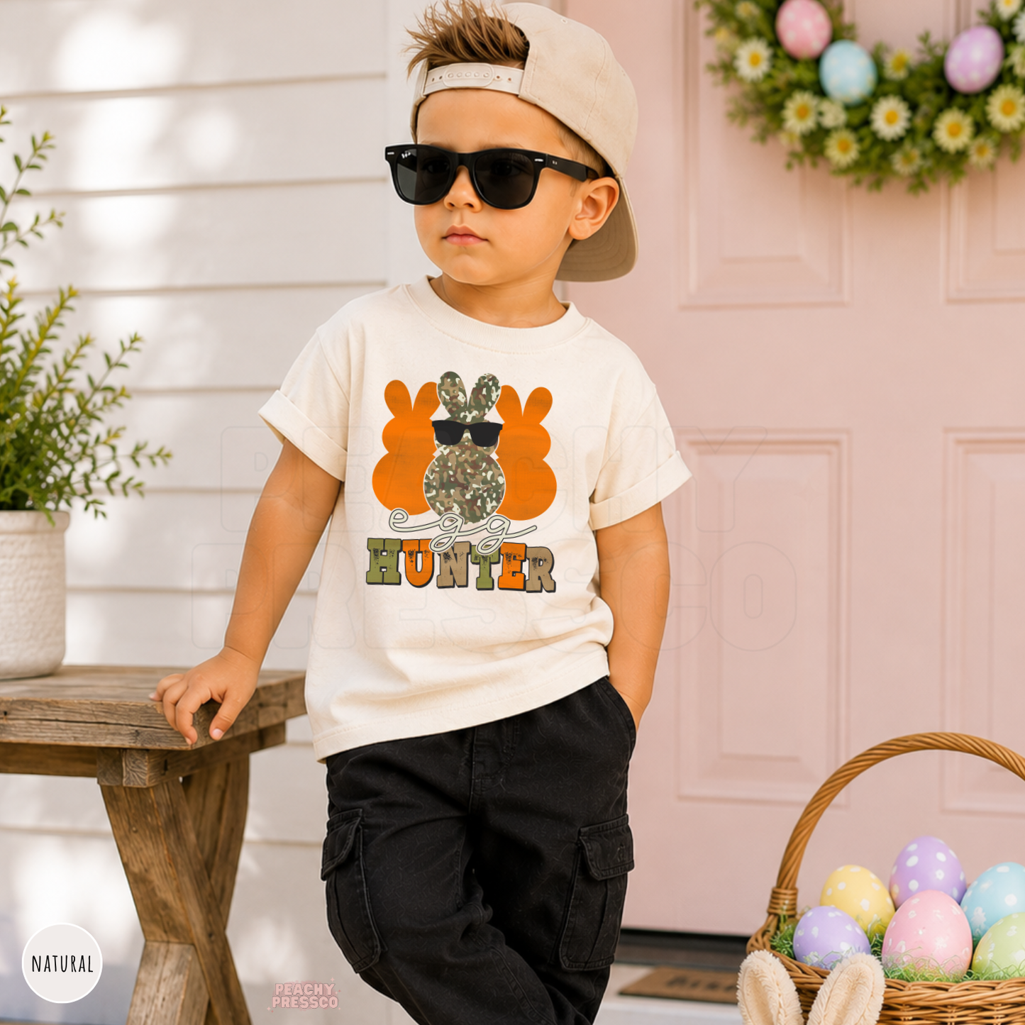 Toddler boy wearing a natural Egg Hunter Easter tee featuring a camouflage bunny with sunglasses and vintage Easter style.