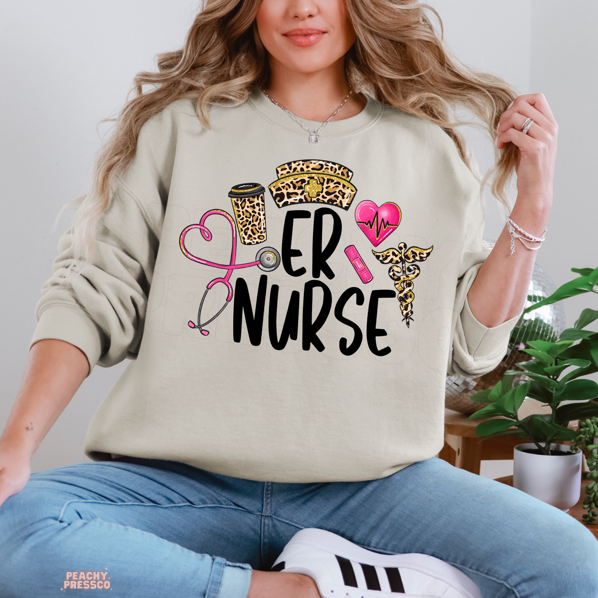 Sand coloured ER Nurse sweatshirt featuring leopard print coffee cup and nurse hat, pink stethoscope and heartbeat heart design.