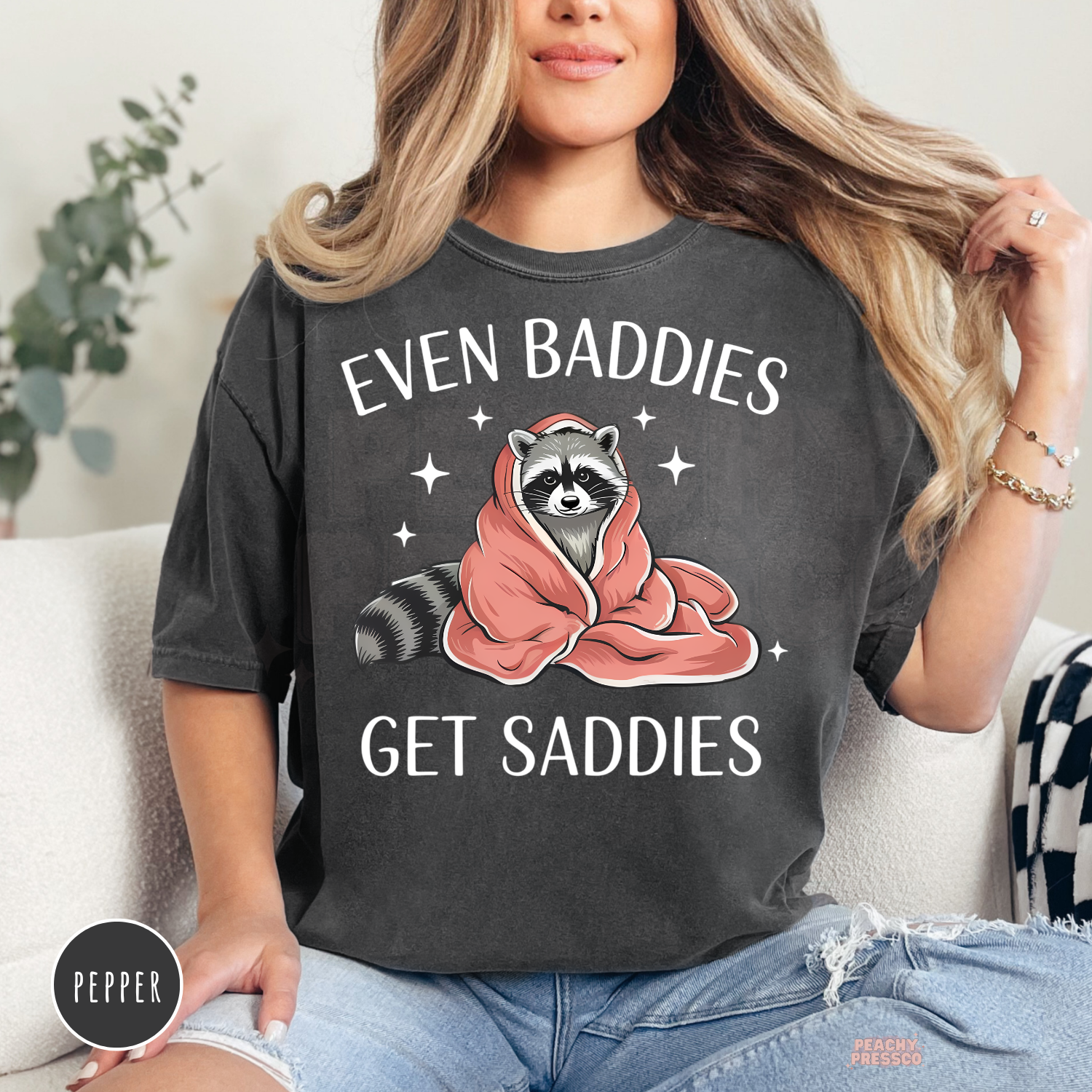 Pepper Comfort Colors graphic t-shirt featuring a cozy raccoon wrapped in a pink blanket with the funny quote "Even Baddies Get Saddies."