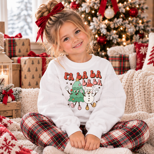 Girl wearing a white Fa La La kids Christmas crewneck featuring a cute Christmas tree and snowman design