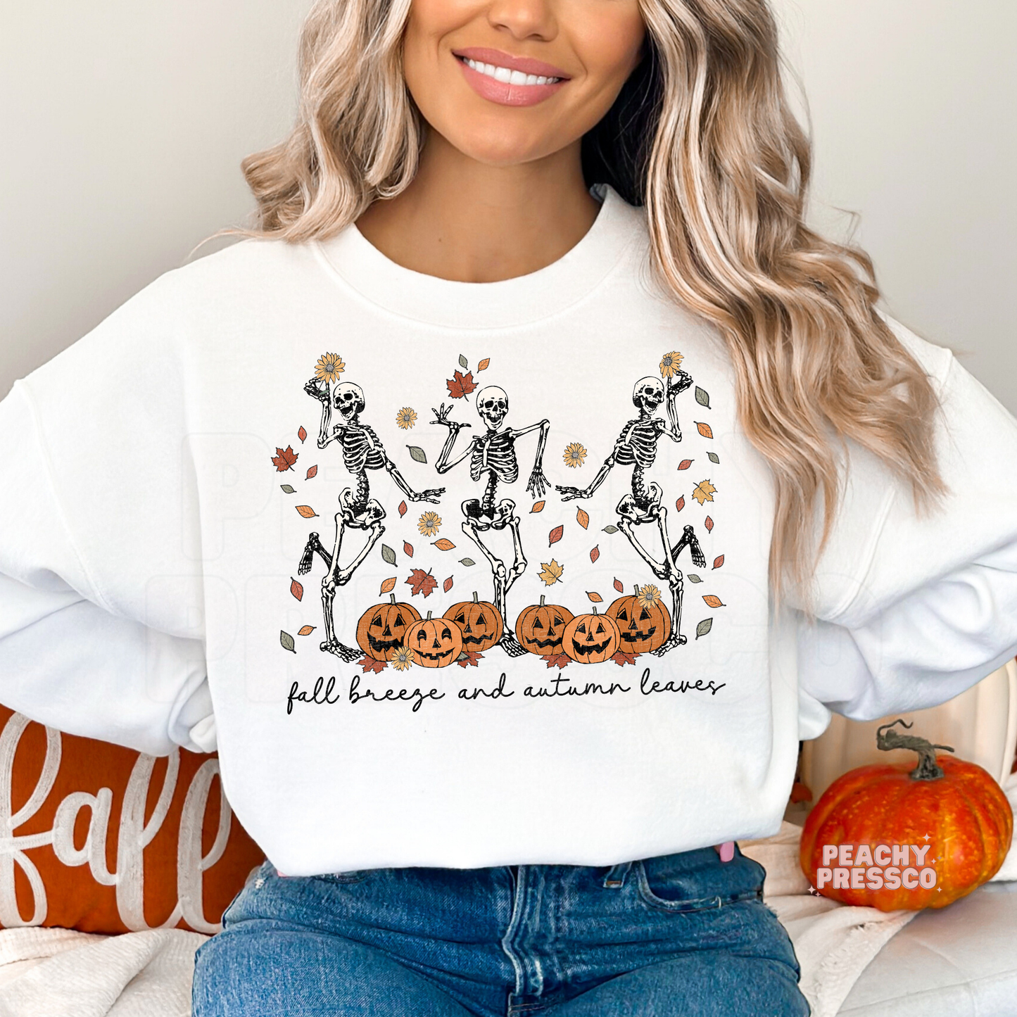 Woman wearing a white sweatshirt with retro dancing skeletons, pumpkins, autumn leaves, and "Fall Breeze and Autumn Leaves" Halloween graphic.