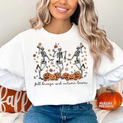 Woman wearing a white sweatshirt with retro dancing skeletons, pumpkins, autumn leaves, and "Fall Breeze and Autumn Leaves" Halloween graphic.