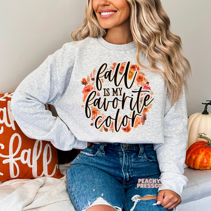 Woman wearing an ash grey crewneck sweatshirt with a floral fall wreath graphic and the phrase "Fall Is My Favorite Color."