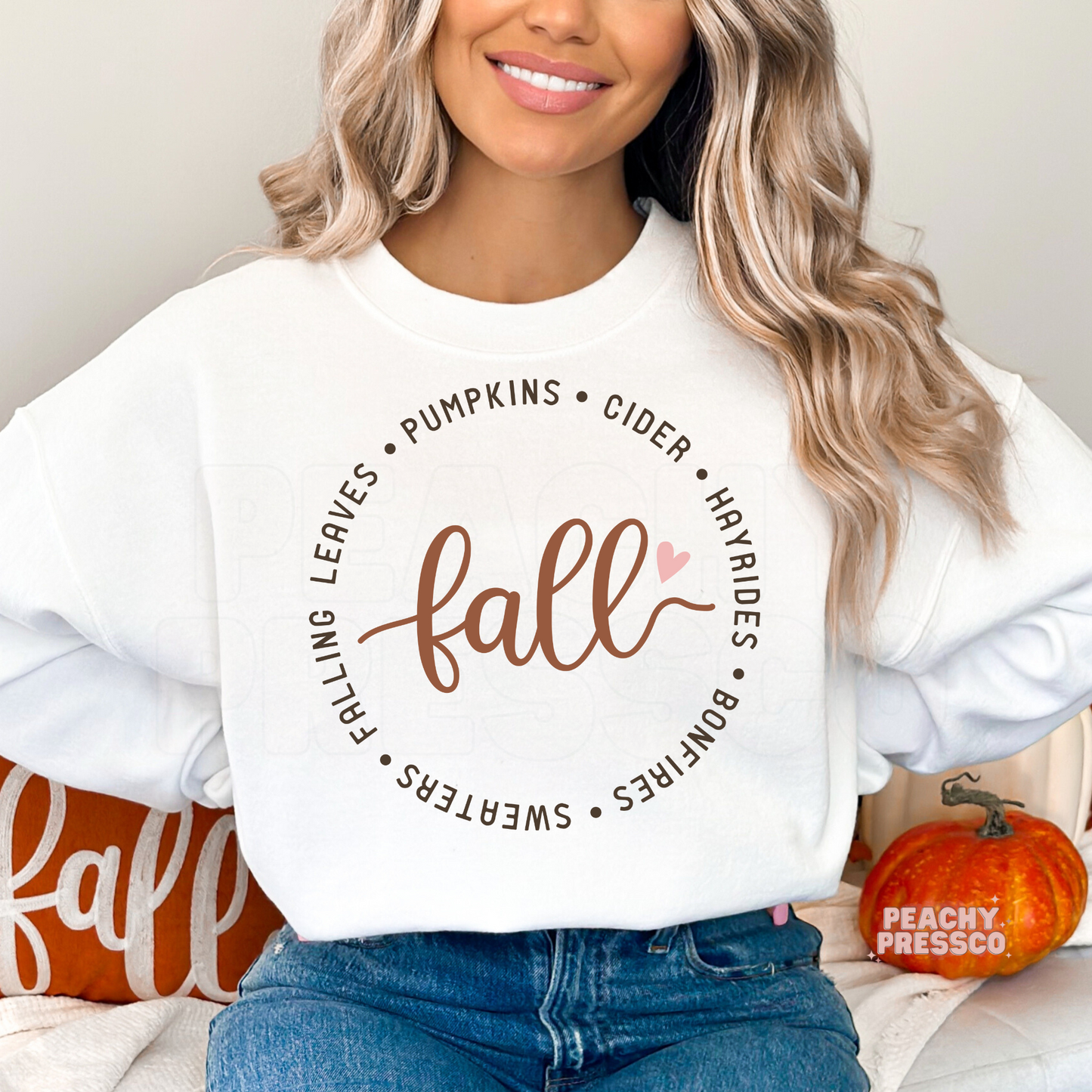 Woman wearing a white graphic t-shirt with a minimalist autumn design celebrating pumpkins, hayrides, cider, bonfires, cozy sweaters, and fall leaves.