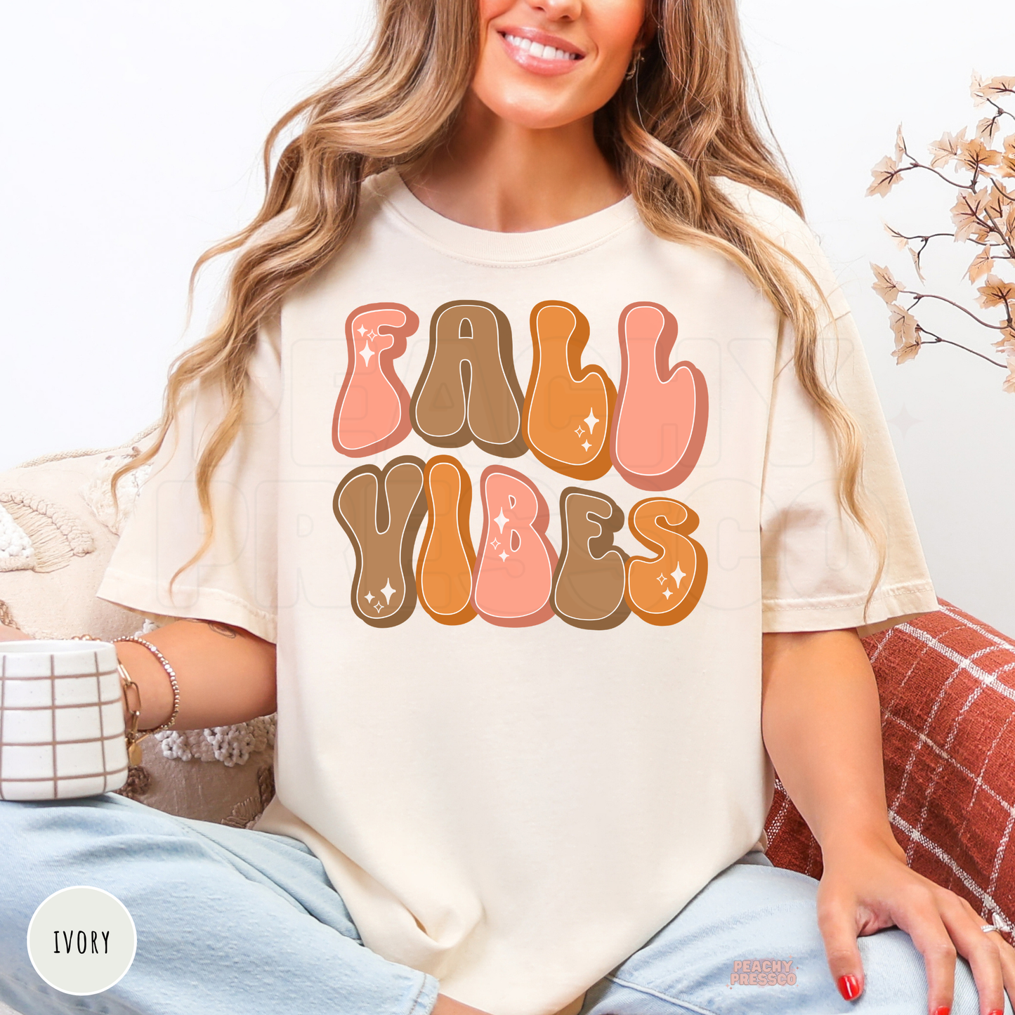 Woman wearing an ivory Comfort Colors t-shirt with a retro "Fall Vibes" graphic in warm autumn colors, perfect for cozy fall outfits.