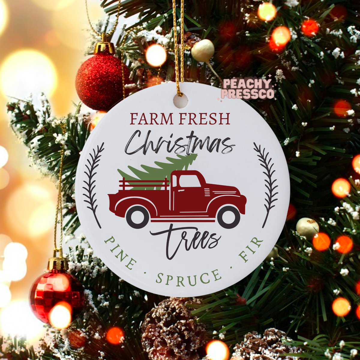 Ceramic holiday ornament hanging on a Christmas tree displaying a red pickup truck carrying a pine tree with Farm Fresh Christmas Trees text.