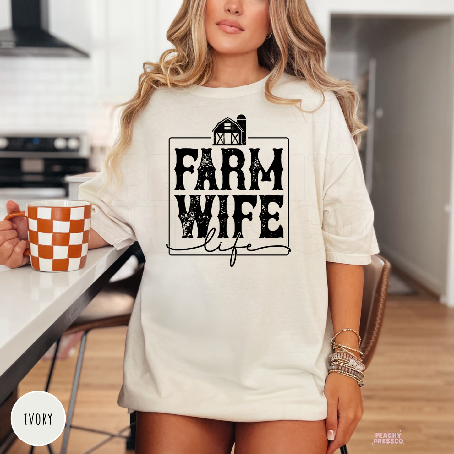 Woman wearing an ivory Farm Wife Life graphic t-shirt featuring a distressed farmhouse design in a modern western country style.