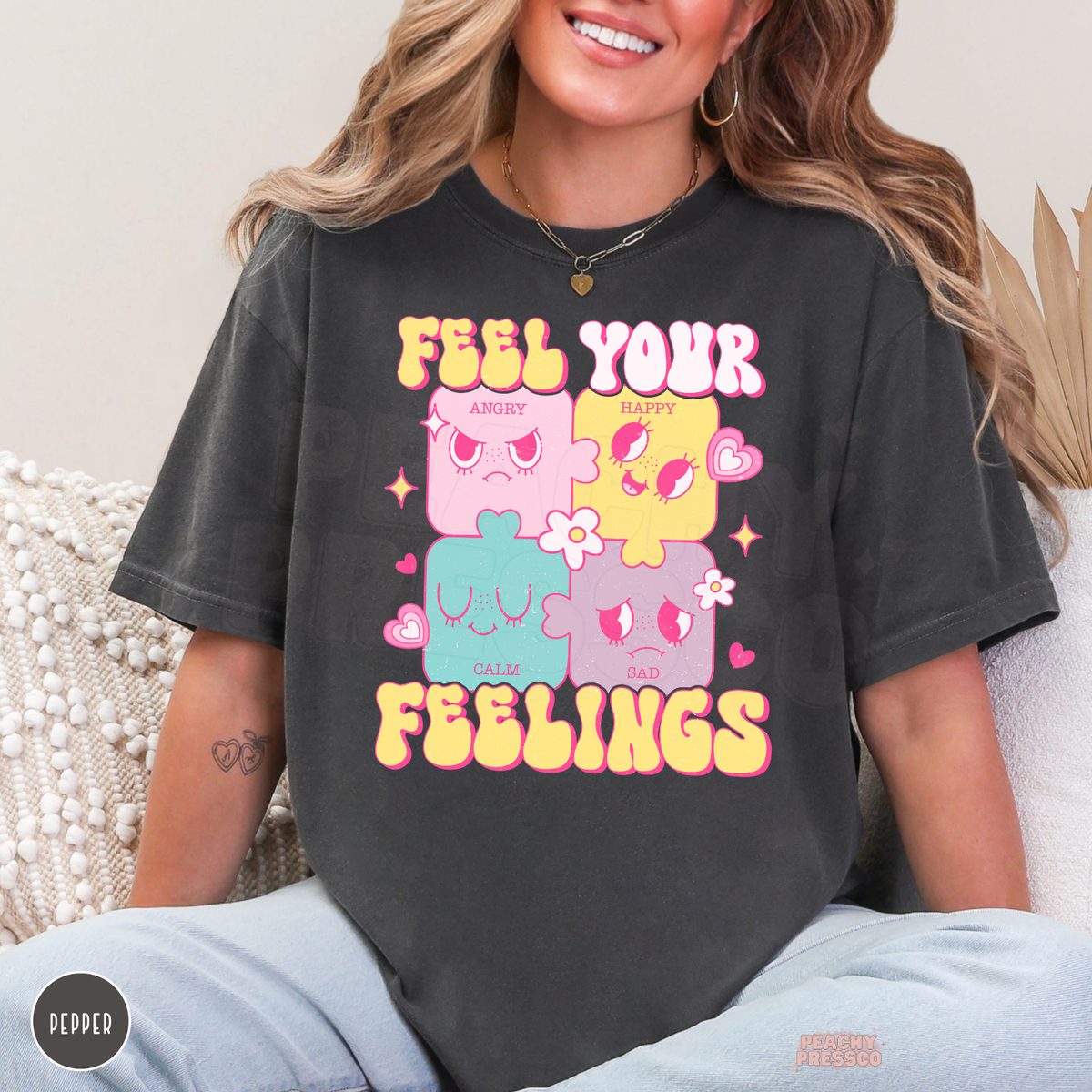 Pepper grey Feel Your Feelings graphic tee featuring bright pink and yellow lettering, four expressive pastel puzzle characters and cute hearts and flowers.
