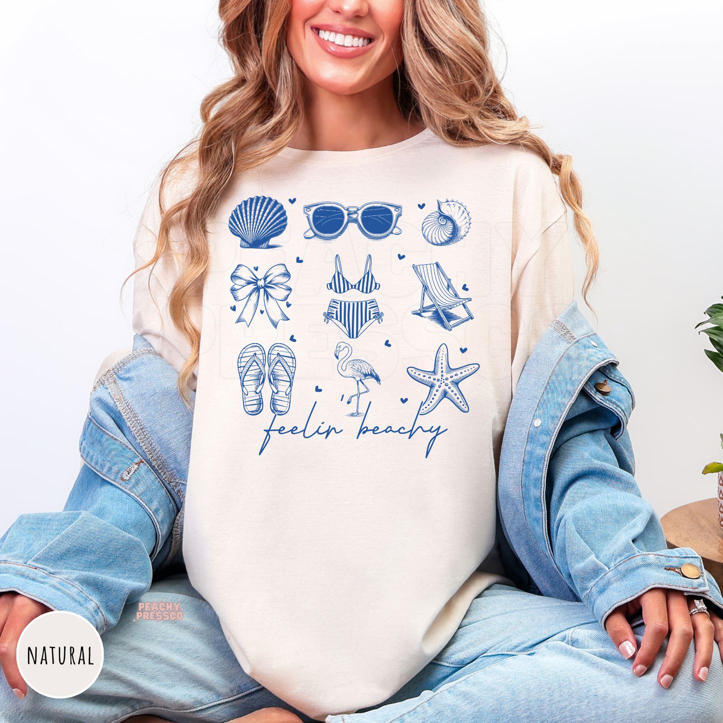 Natural Comfort Colors t-shirt featuring a blue beach-inspired collage with seashells, sunglasses, bow, bikini, beach chair, flamingo, starfish, flip flops, and "Feelin' Beachy."