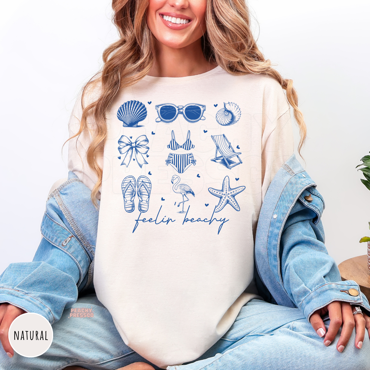 Natural Comfort Colors t-shirt featuring a blue beach-inspired collage with seashells, sunglasses, bow, bikini, beach chair, flamingo, starfish, flip flops, and "Feelin' Beachy."