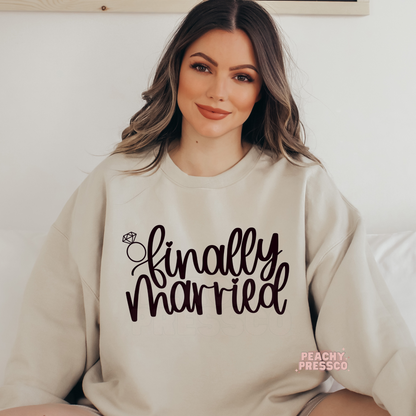 Sand crewneck sweatshirt featuring the "Finally Married" graphic with a diamond ring illustration, ideal for cozy honeymoon wear, wedding celebrations, and newlywed gifts.