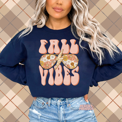 Woman wearing a navy crewneck sweatshirt featuring a retro Fall Vibes graphic with floral sunglasses and a leopard lightning bolt.