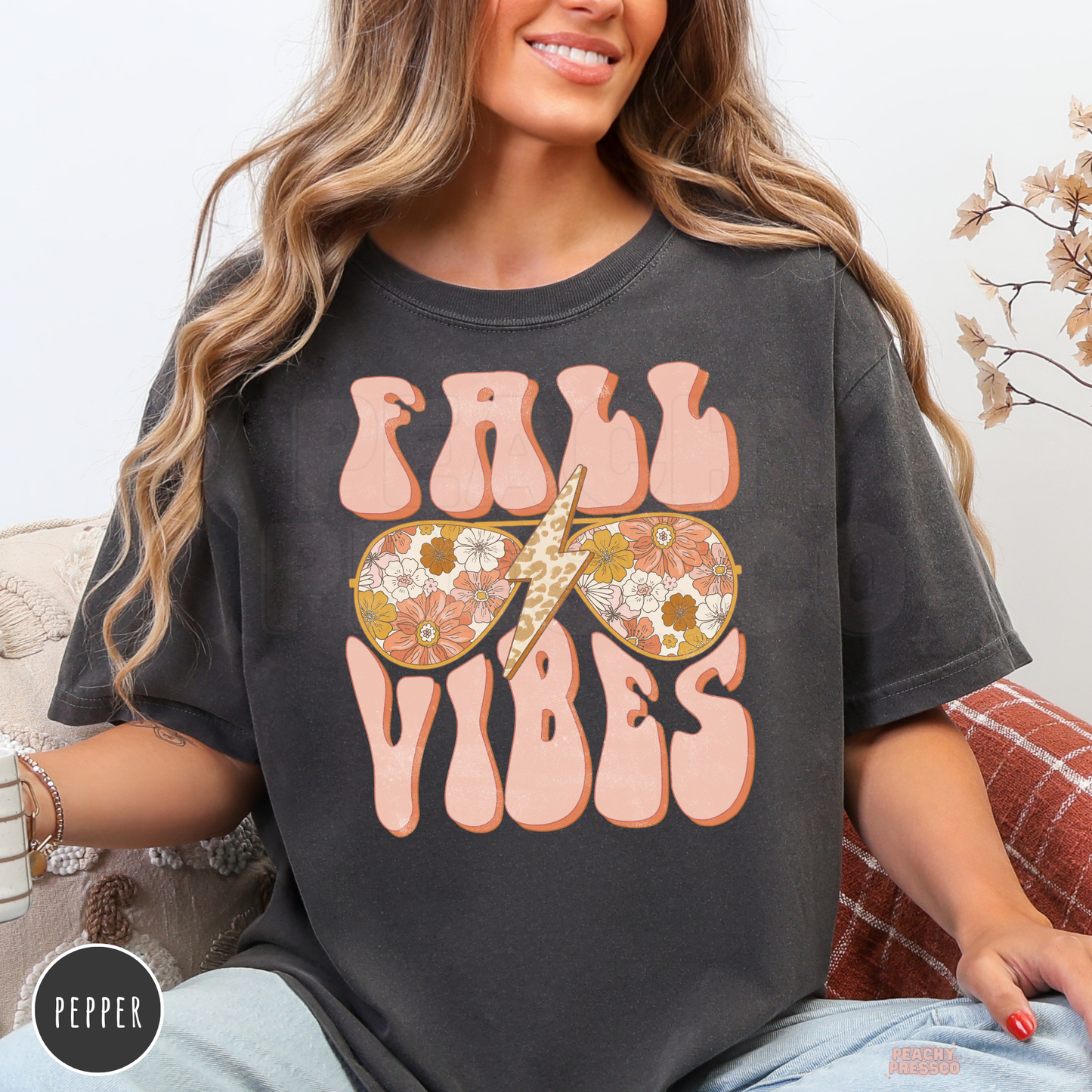 Woman wearing a pepper Comfort Colors graphic t-shirt featuring a retro Fall Vibes design with floral sunglasses and a leopard lightning bolt.