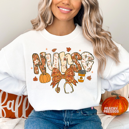 Woman wearing a white crewneck sweatshirt featuring a floral "Nurse" design with pumpkin spice coffee, pumpkin, stethoscope bow, and cozy fall elements.