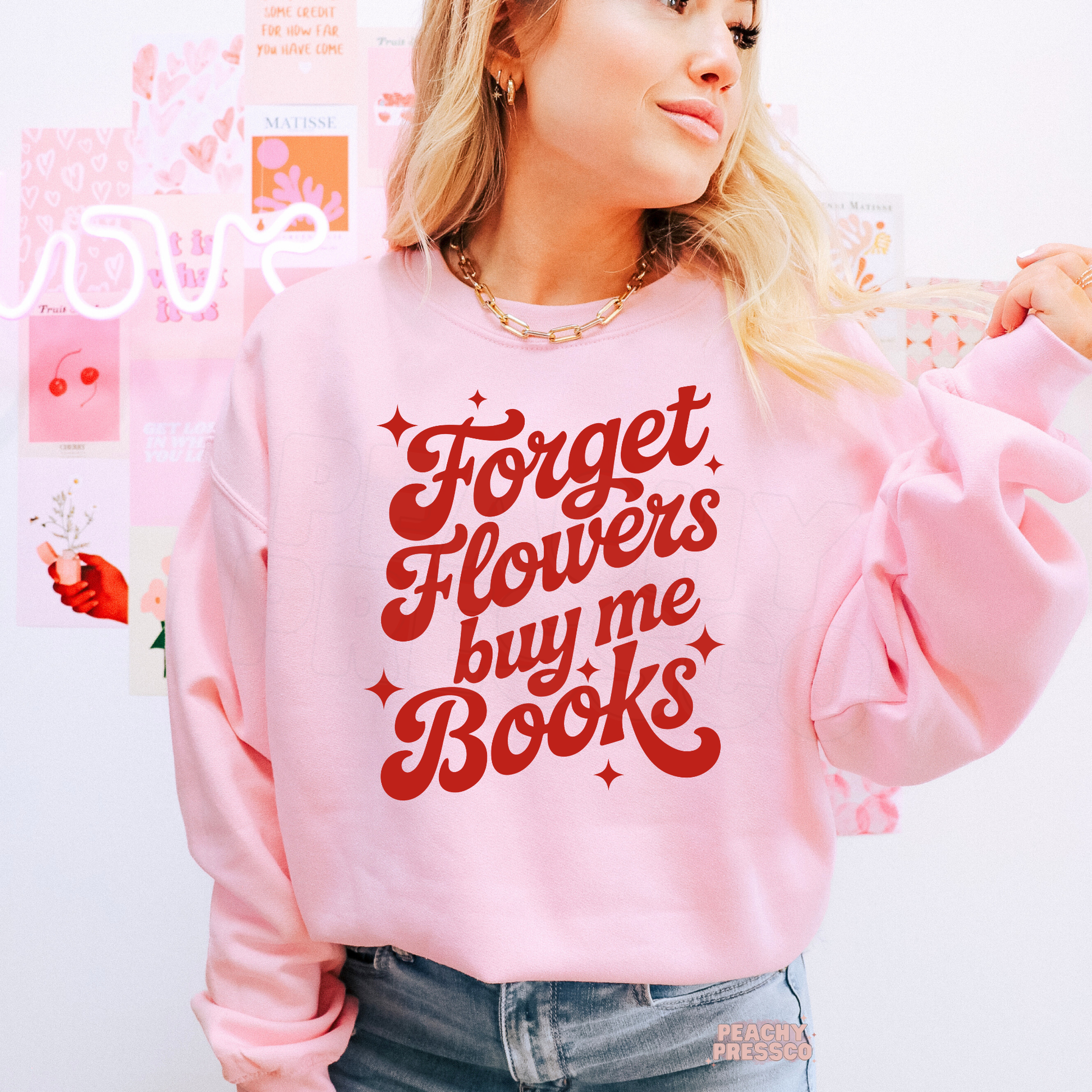 Light pink sweatshirt with the playful "Forget Flowers Buy Me Books" quote in vintage-inspired red typography for readers.
