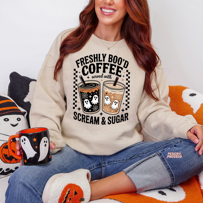 Woman wearing a sand Halloween crewneck sweatshirt featuring the Freshly Boo'd Coffee Served with Scream & Sugar ghost coffee graphic and cozy fall aesthetic.