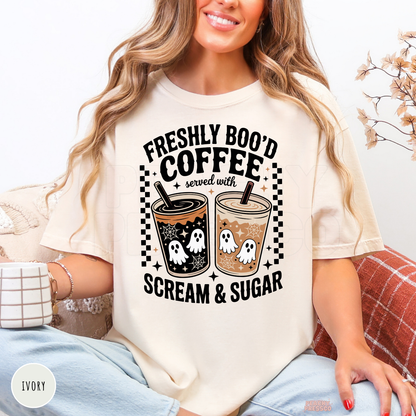 Woman wearing an ivory Halloween t-shirt featuring a Freshly Boo'd Coffee Served with Scream & Sugar design with spooky ghost iced coffees and fall coffee aesthetic.