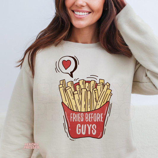 Sand crewneck sweatshirt showcasing a fun "Fries Before Guys" graphic with illustrated french fries and a heart conversation bubble.