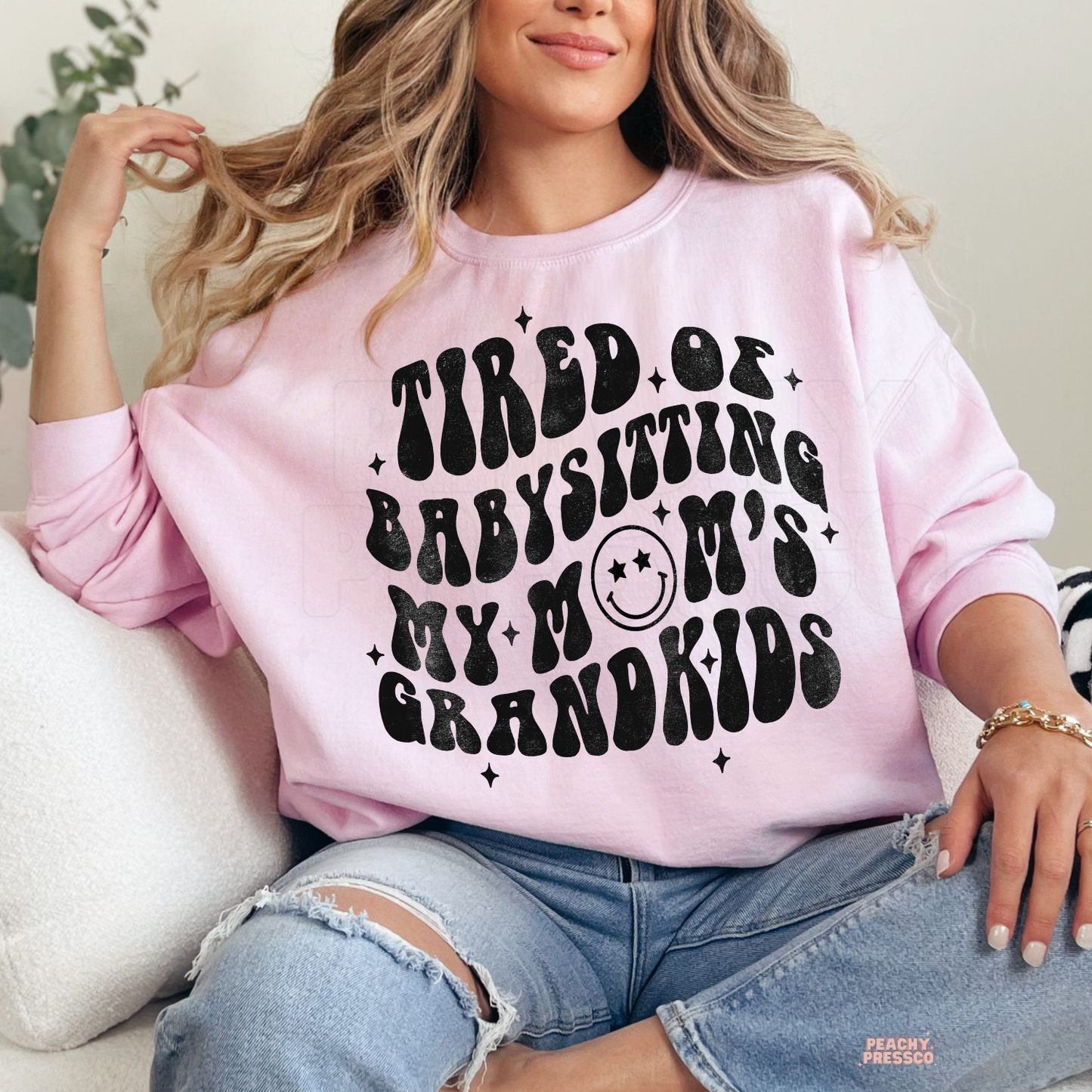 Light pink sweatshirt featuring the funny quote "Tired of Babysitting My Mom's Grandkids" in retro black lettering. Humorous mom sweatshirt for busy moms.