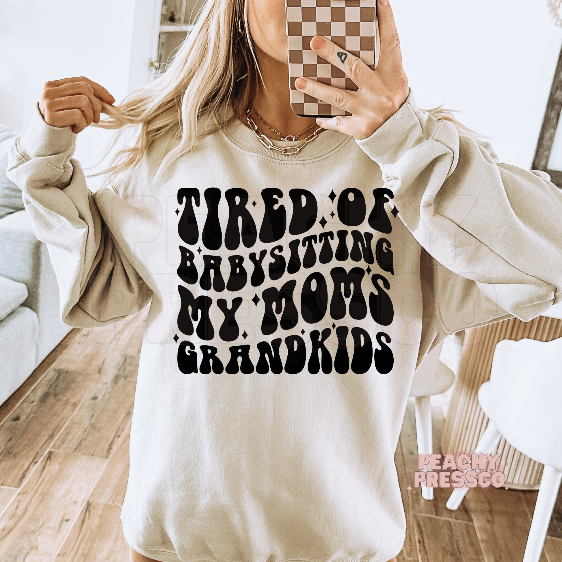 Sand sweatshirt featuring the humorous "Tired of Babysitting My Mom's Grandkids" design in vintage-style lettering. Funny mama sweatshirt for everyday wear.
