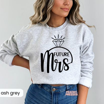 Ash grey crewneck sweatshirt featuring a black "Future Mrs" engagement ring design, ideal for brides-to-be, bridal showers, engagement announcements, wedding weekends, and everyday bridal style.