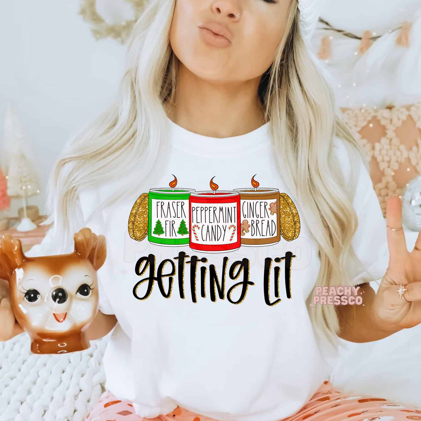 Women making a peace sign wearing a white t-shirt printed with Fraser Fir, Peppermint Candy, and Gingerbread candles.