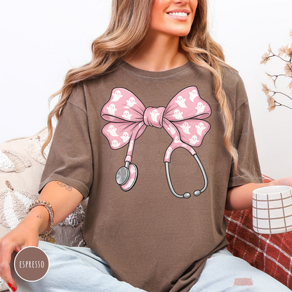 Woman wearing an espresso brown t-shirt featuring a pink ghost stethoscope bow graphic for nurses, doctors, CNAs, and spooky season.