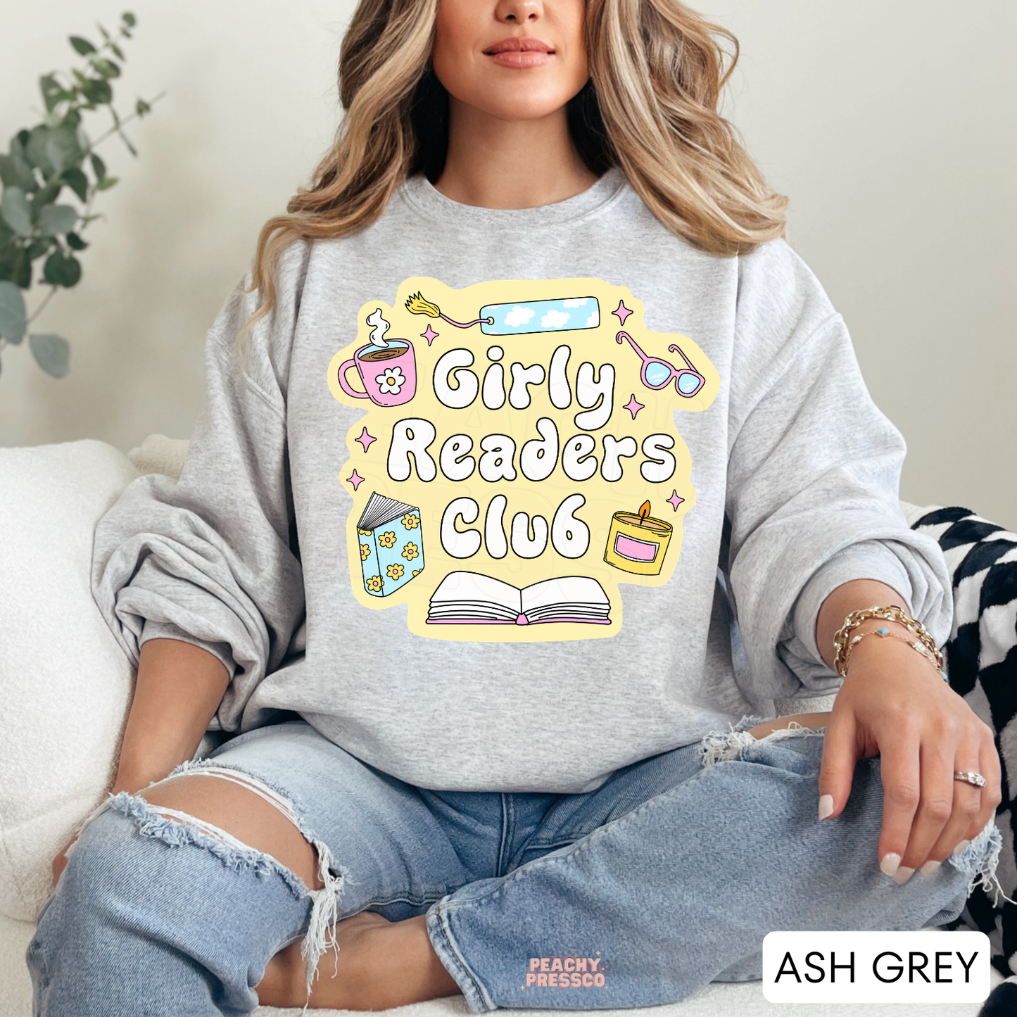 Ash Grey crewneck sweatshirt with Girly Readers Club graphic featuring cozy reading icons including books, coffee, candle, bookmark, and glasses.
