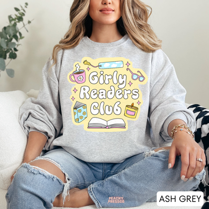 Ash Grey crewneck sweatshirt with Girly Readers Club graphic featuring cozy reading icons including books, coffee, candle, bookmark, and glasses.