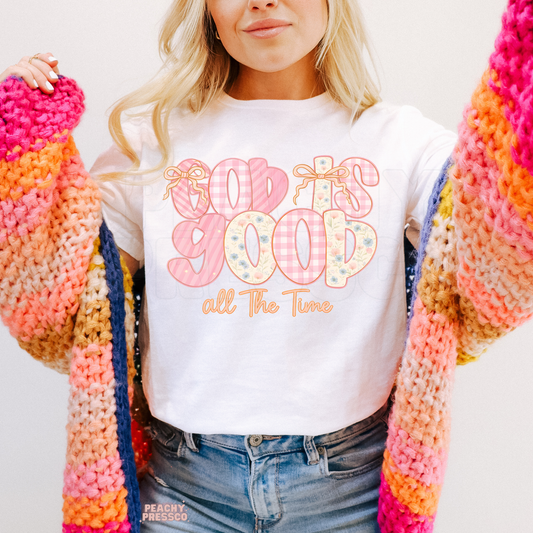 White shirt featuring a pastel "God Is Good All The Time" design with floral and gingham lettering and delicate bows. Cozy unisex Christian sweatshirt perfect for church, Bible study, or everyday wear.