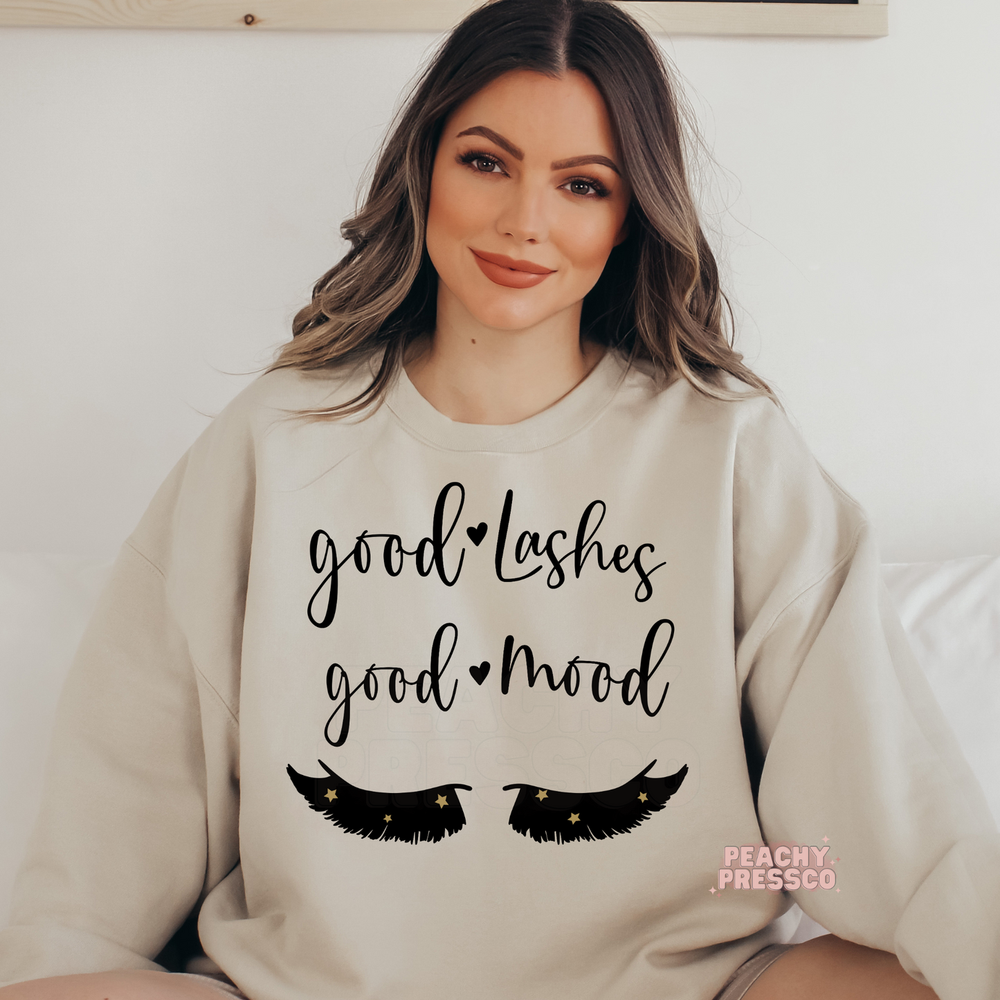 Sand-colored crewneck sweatshirt featuring the Good Lashes Good Mood saying with eyelash design, ideal for lash extension artists, estheticians, and spa professionals.