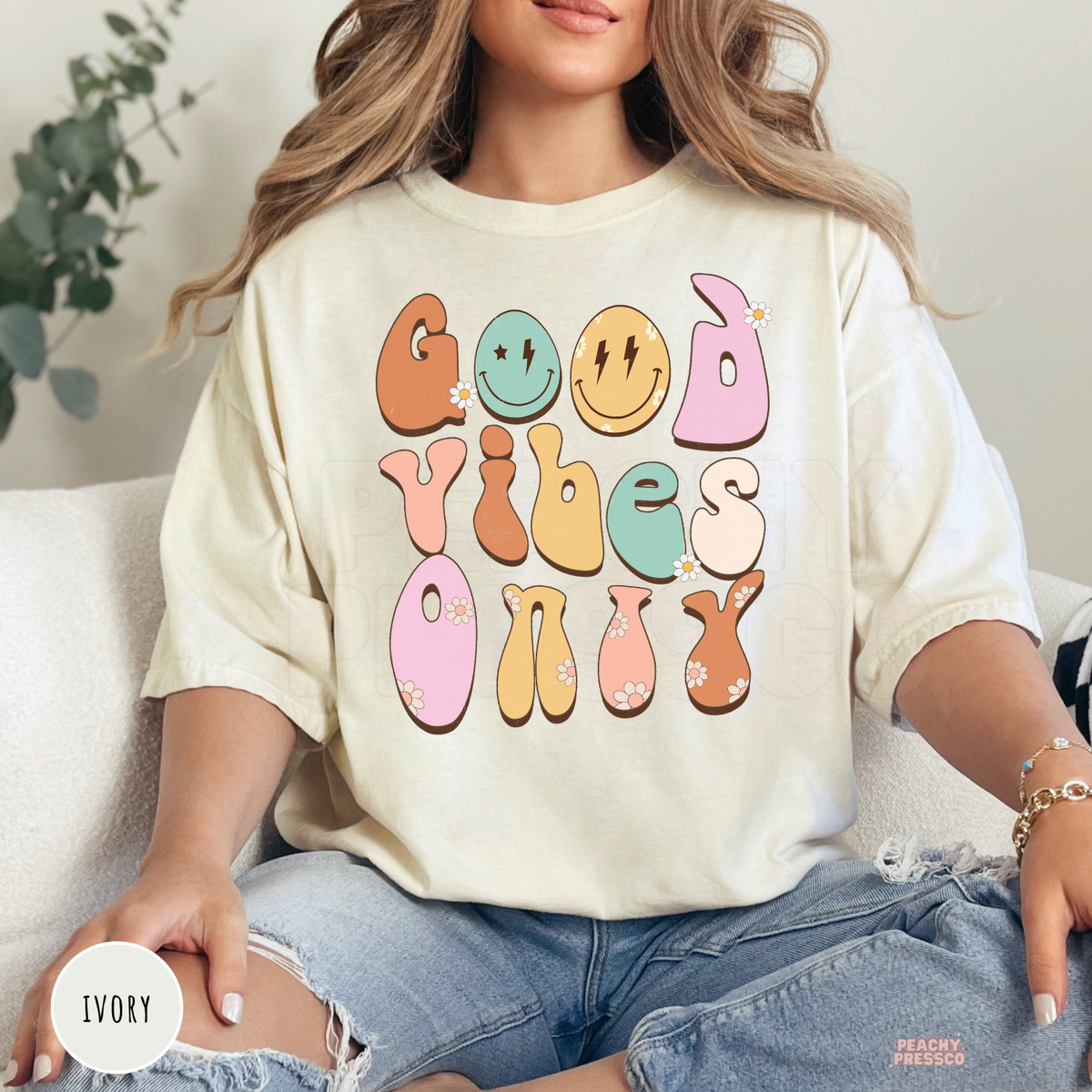 Ivory Comfort Colors t-shirt featuring a retro "Good Vibes Only" design with pastel groovy lettering, smiley faces, daisy flowers, and vintage-inspired colors.