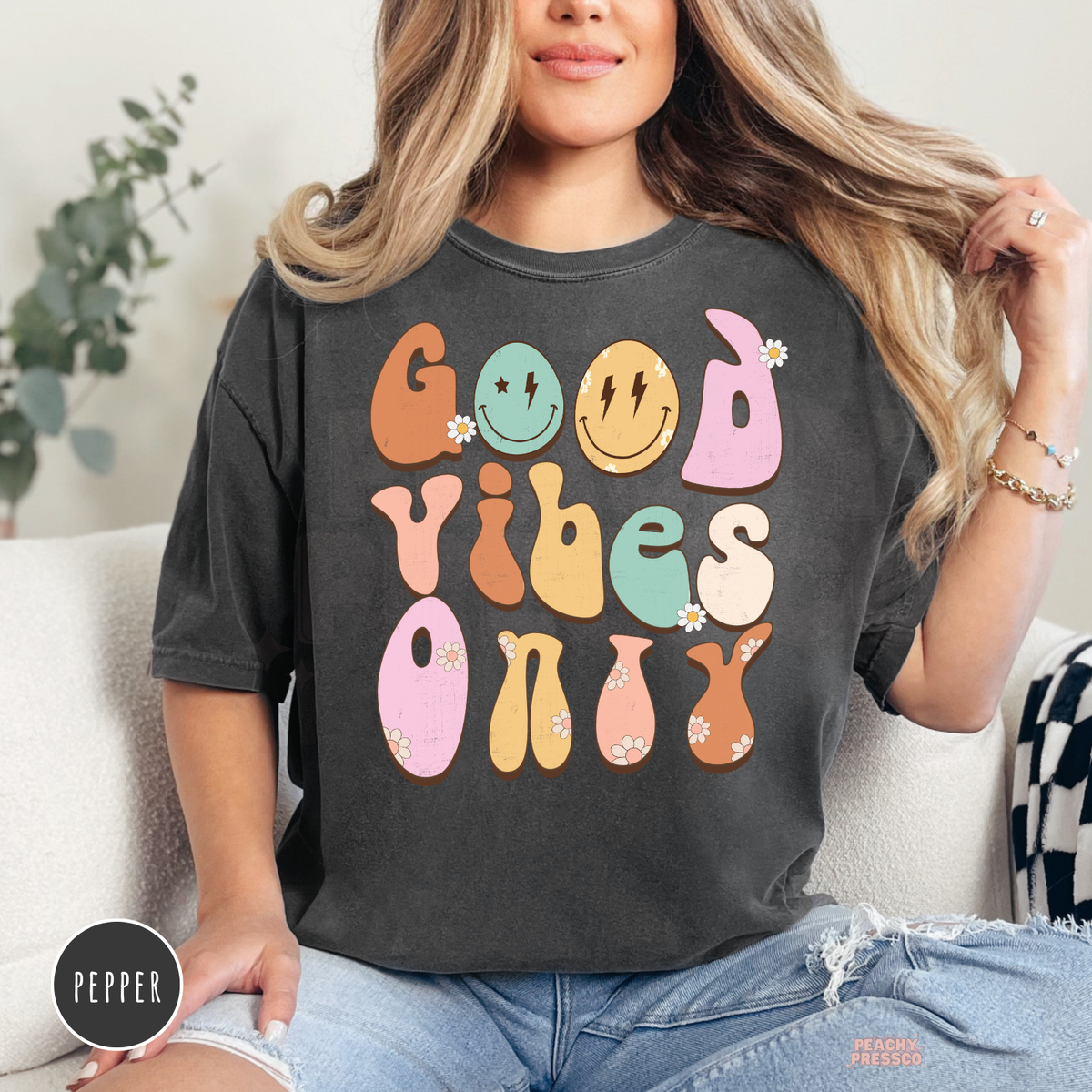 Pepper Comfort Colors t-shirt displaying a retro "Good Vibes Only" graphic with pastel groovy lettering, smiley faces, daisy flowers, and a trendy vintage aesthetic.